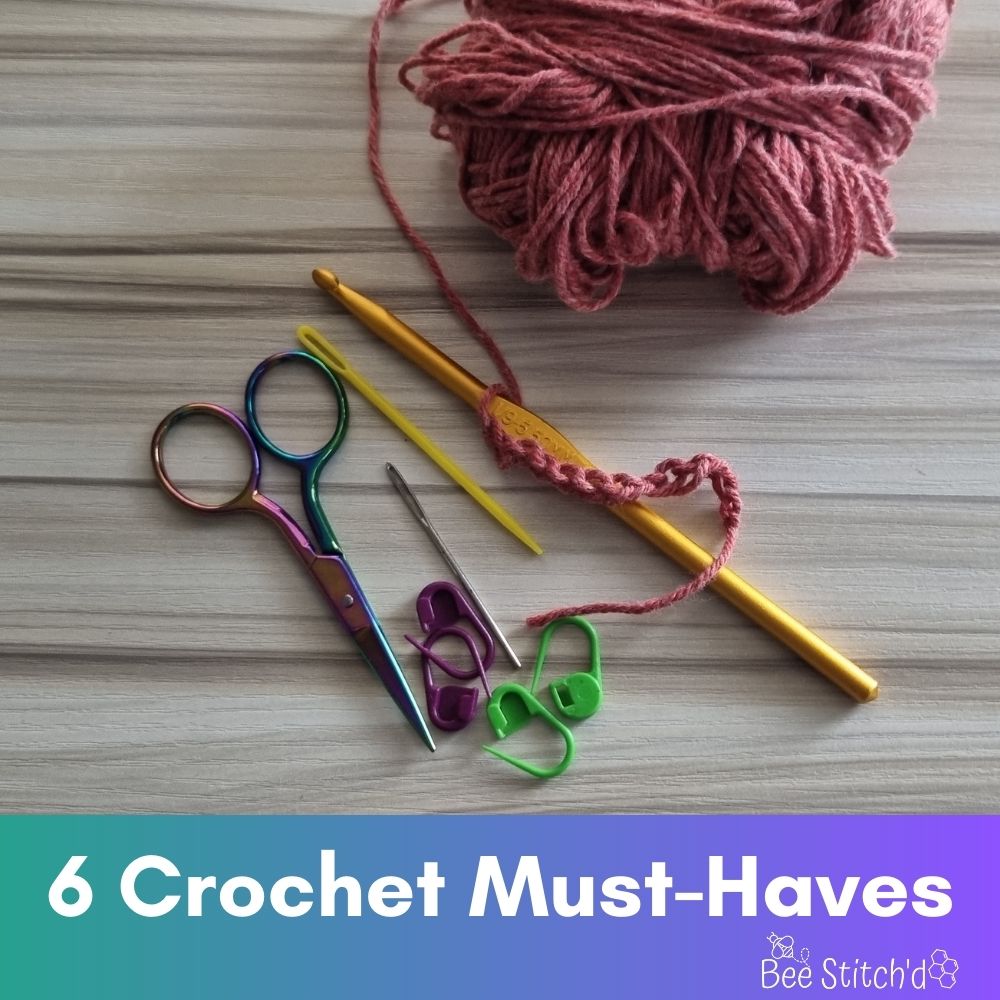 image says "6 crochet must haves" with a picture of scissors, stitch markers, crochet hook, yarn, and yarn needle